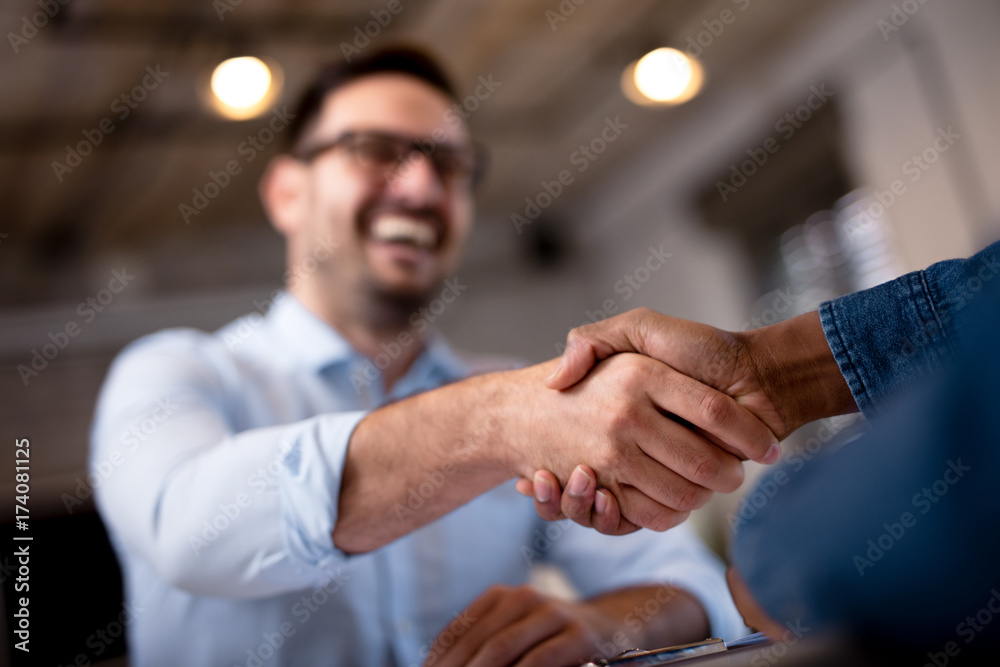 Zwei Personen geben sich lächelnd die Hand als Symbol für eine herzliche Begrüßung im Team